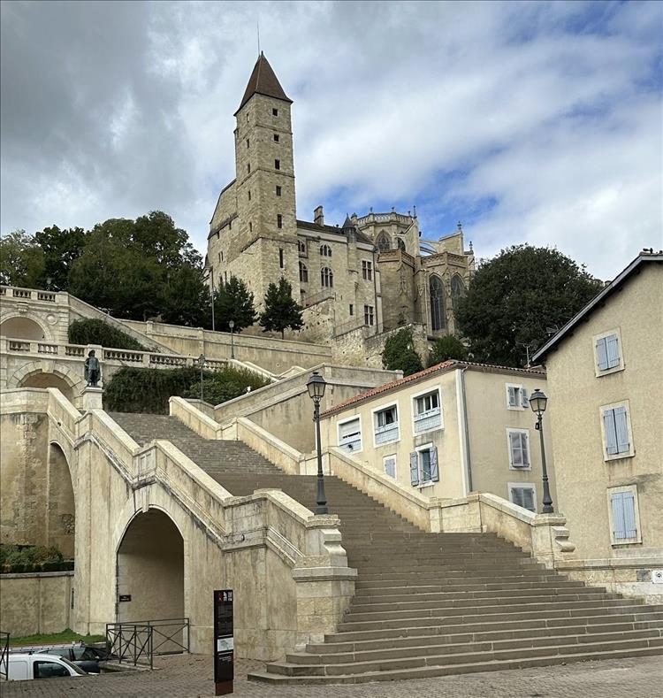 Up a huge flight of stone steps, between buildings and trees the tower and church of a small cathedral