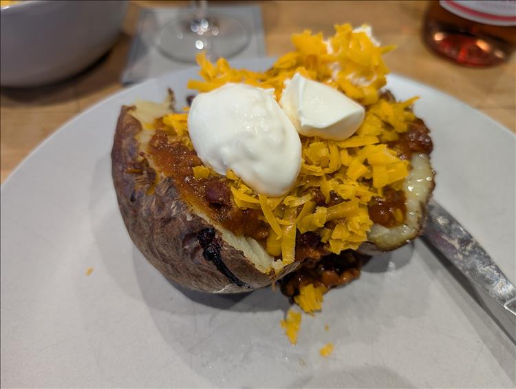 A baked potato split and filled with chilli, cheese and sauce