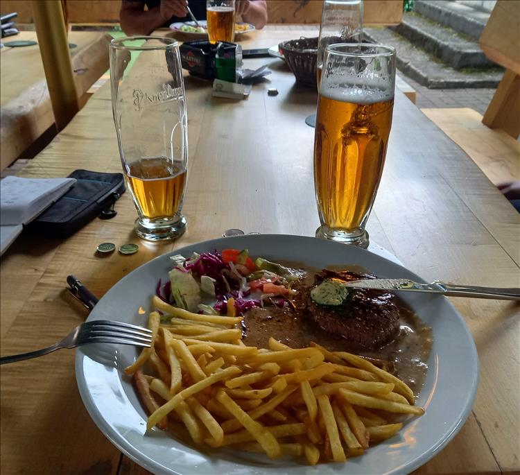 A few beers on a table and a plate of chips and steak and veg