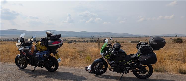 The 2 bikes set against dry arid fields and hills in the distance