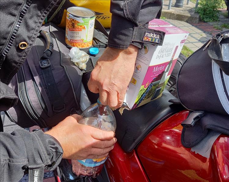 A rider draining wine from a box into bottles he has with him