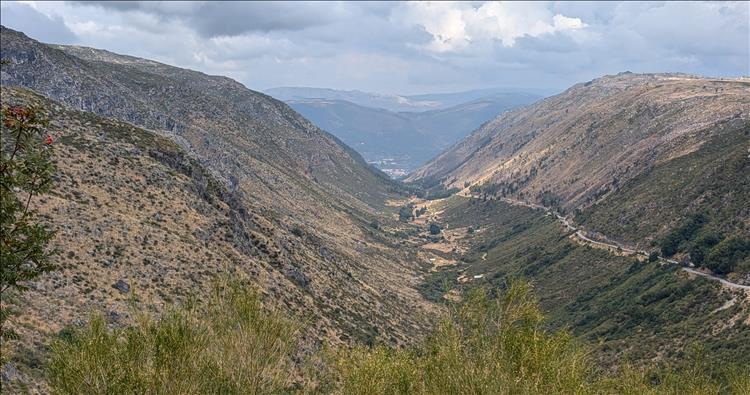 A deep valley and sinuous road leading downhill for miles