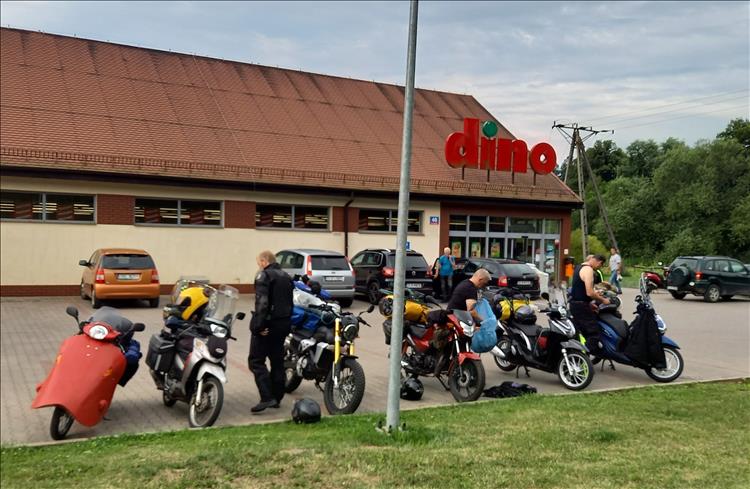 The six small capacity bikes outside a shop with a sign stating "DINO" in Poland