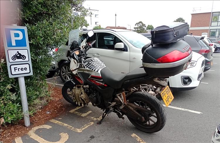 Ren's 500 parked next to a sign declaring motorcycle parking is free