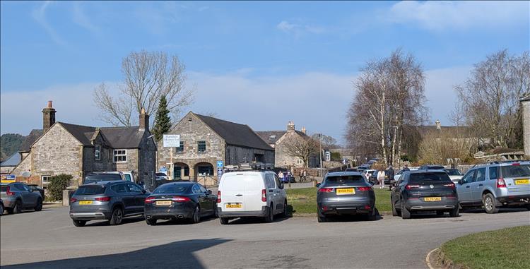 Among the stone cottages and trees a lot of parked cars in Hartington
