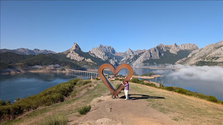 A large and lightly rusty metal object in the shape of a heart set against the backdrop of the wonderful mountains