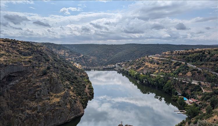 A once deep and steep gorge filled with water and the top of the dam is visible