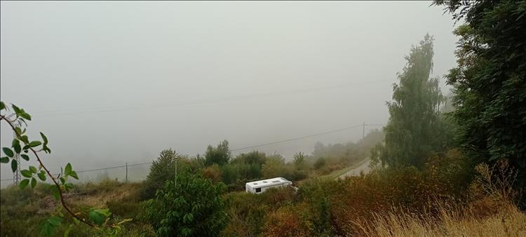 Looking down a hill we see a road and a camper van, otherwise it's all mist