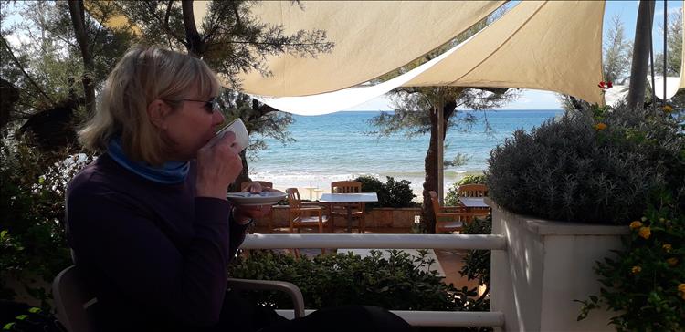 Mrs Upt's sips coffee overlooking the sea in a coastal cafe