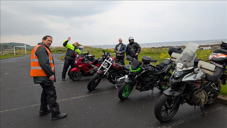4 riders in wet weather gear, 5 motorcycles in the rain beside the misty coast of Ayrshire