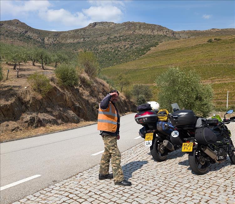 Ren sheilds his eyes from the sun, stood by the motorcycles in the wonderful Douro valley