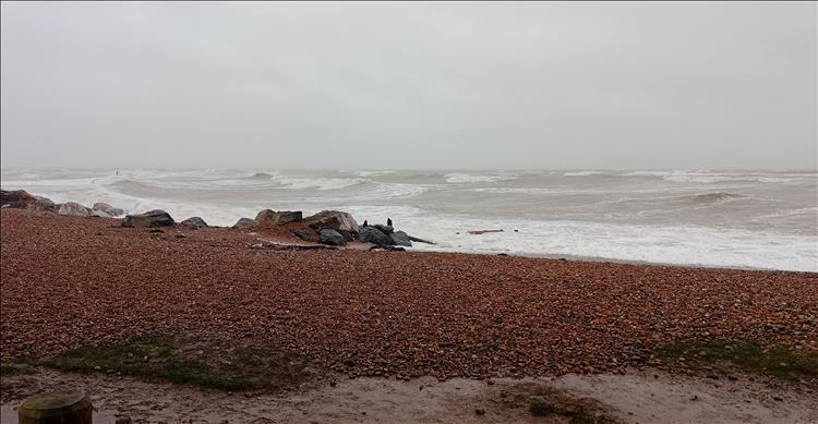 A stone and pebble beach and rough choppy grey brown seas at Worthing