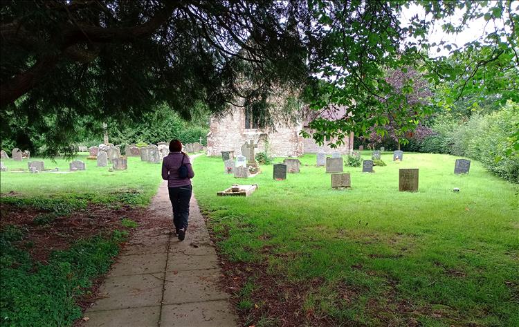 Sharon walks to the old stone church among the gravestones