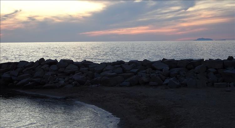 Sunset over the sea, a beach and a stone groyne makes a pretty picture