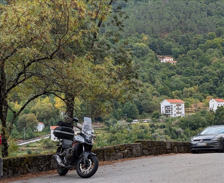 The CB500X parked across the road with trees and the valley