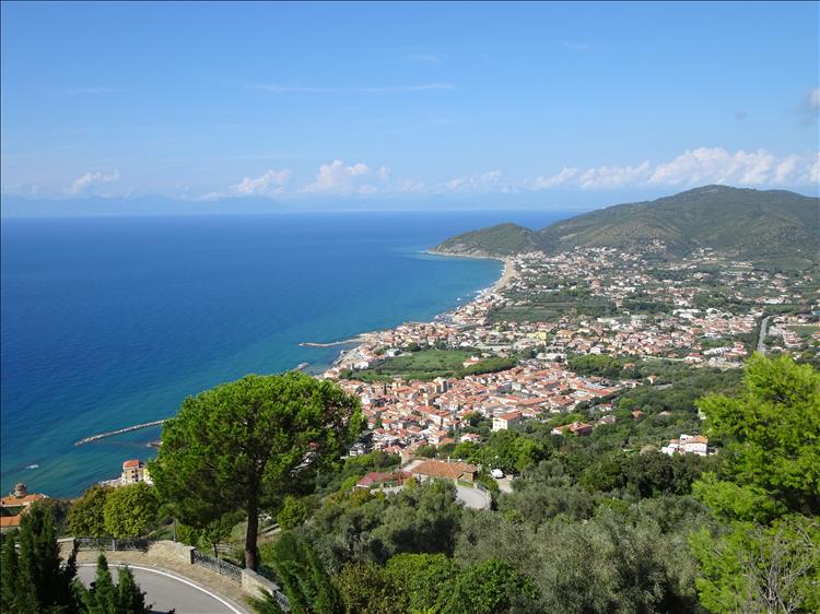 From high in a mountain looking down over blue seas and a town by the coast