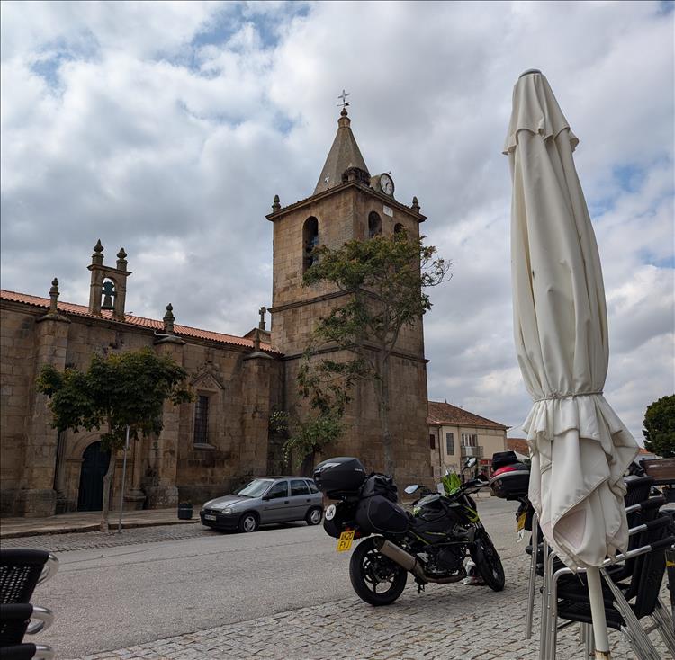 A stout church with square tower in the spanish style seen from the cafe