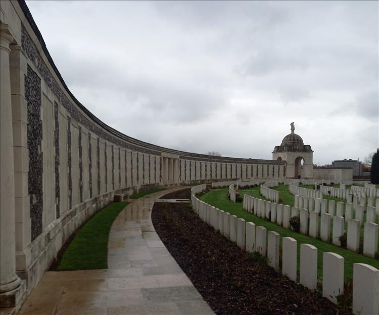 A very long curved and tall wall filled with many thousand of names at the cemetery