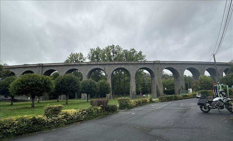 A long multi arched brigge built in stone against grey skies and trees