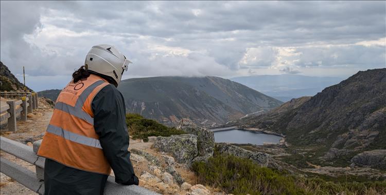 Ren looks over a barrier to the mountains and reservoir