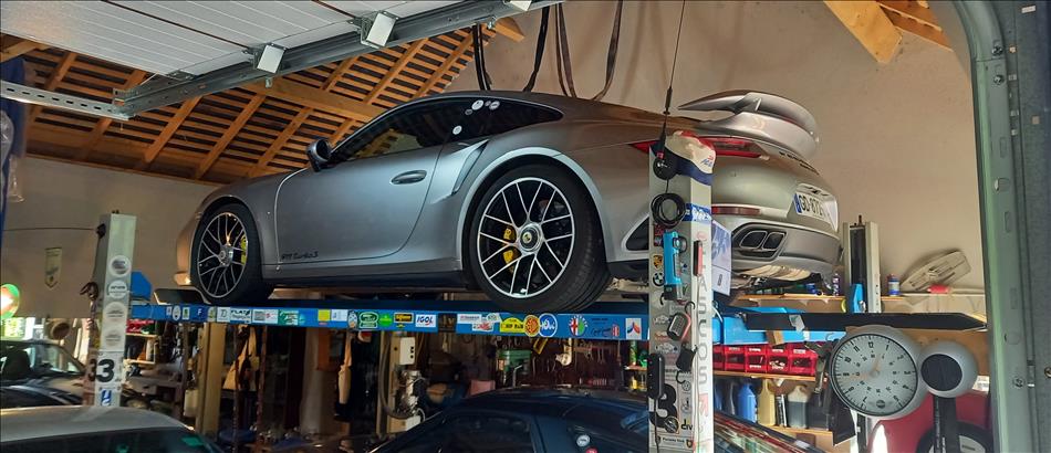 Porsche 911 GTs on a ramp, we can see the roofs of other fast cars below