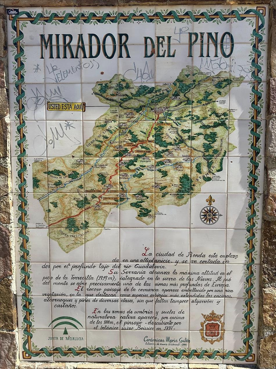 A sign showing text and a map of a route heading through mountains