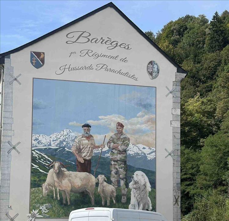 A large mural on the gable end of a house - of a farmer, a military man, and some cattle