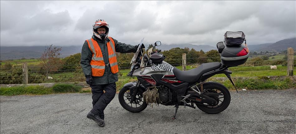 Ren in waterproof and hi viz stood beside his dirty CB500X
