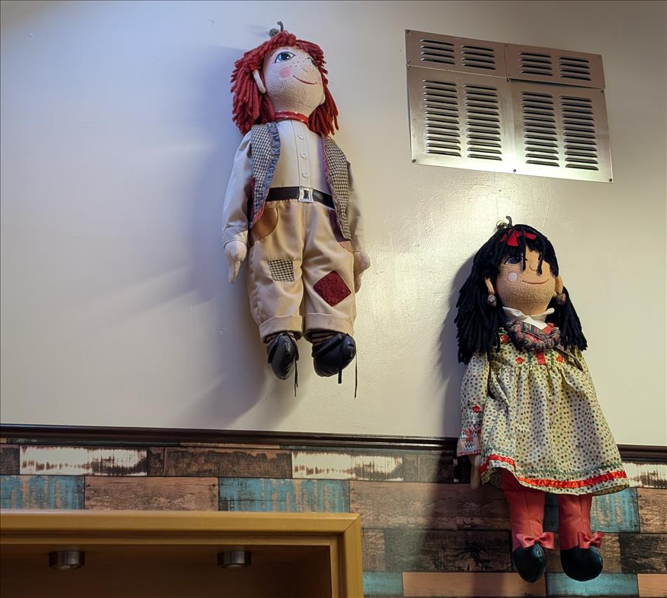 Rosie and Jum soft dolls hanging on a wall at the cafe