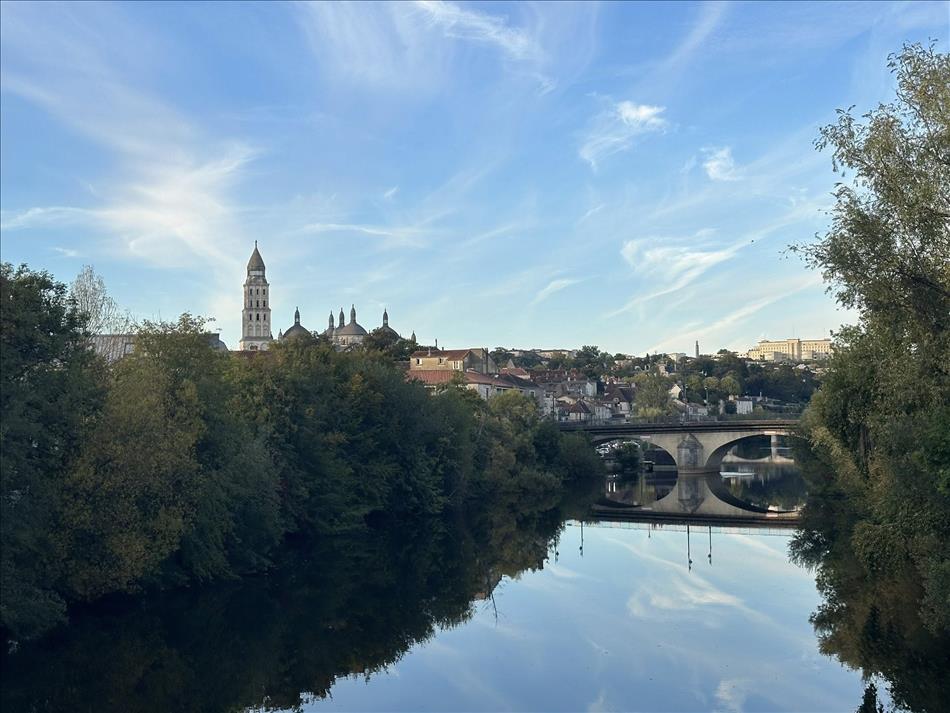 A town, a tower, a river and a bridge, all perfectly reflected in the very still river