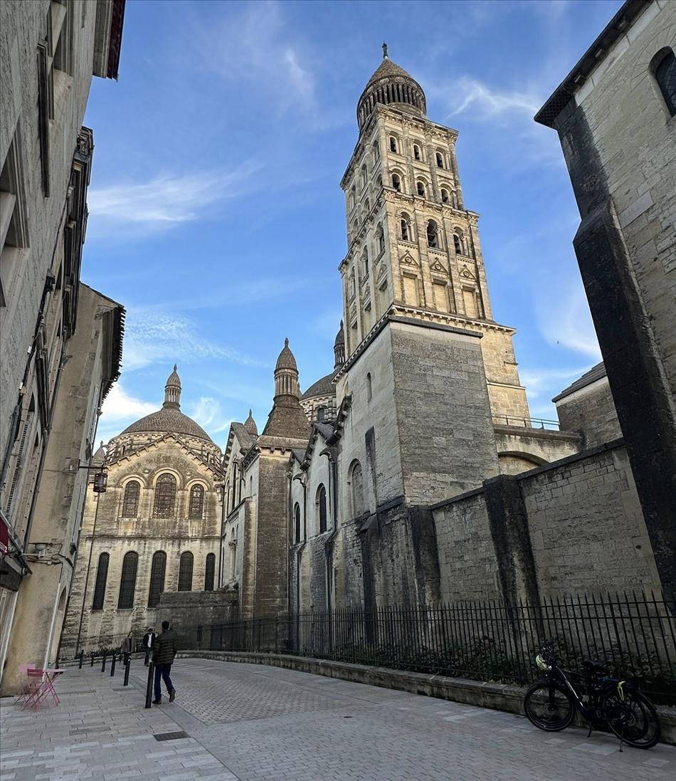 A tower and several building down a stone road, all in a light coloured stone looking old