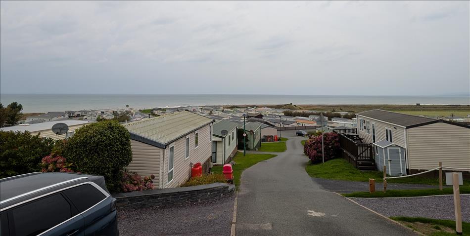 Looking down from a vantage point there's static caravans, roads, grass and then the shoreline and sea