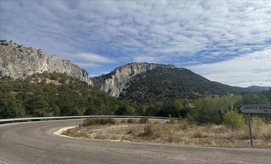 A curve in the road sweeps through the scene with rocky hilltops with a gap between`