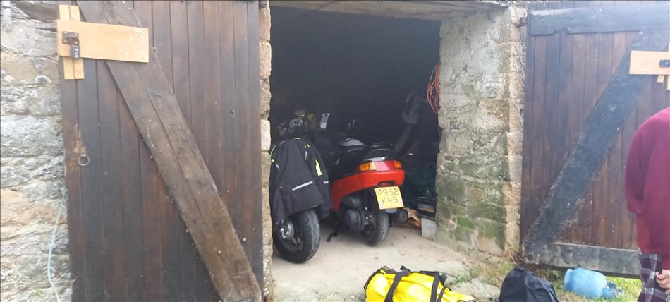 Old wooden doors open to a stone barn with the motorcycles stowed inside