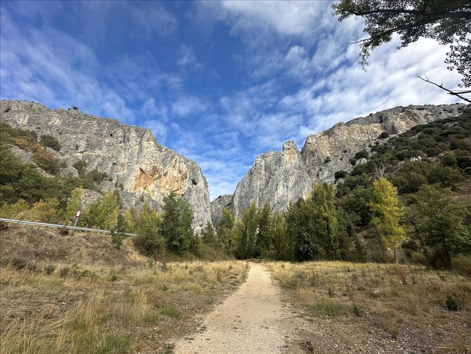 A sandy path leads between two towering rocky walls at the start of the walk