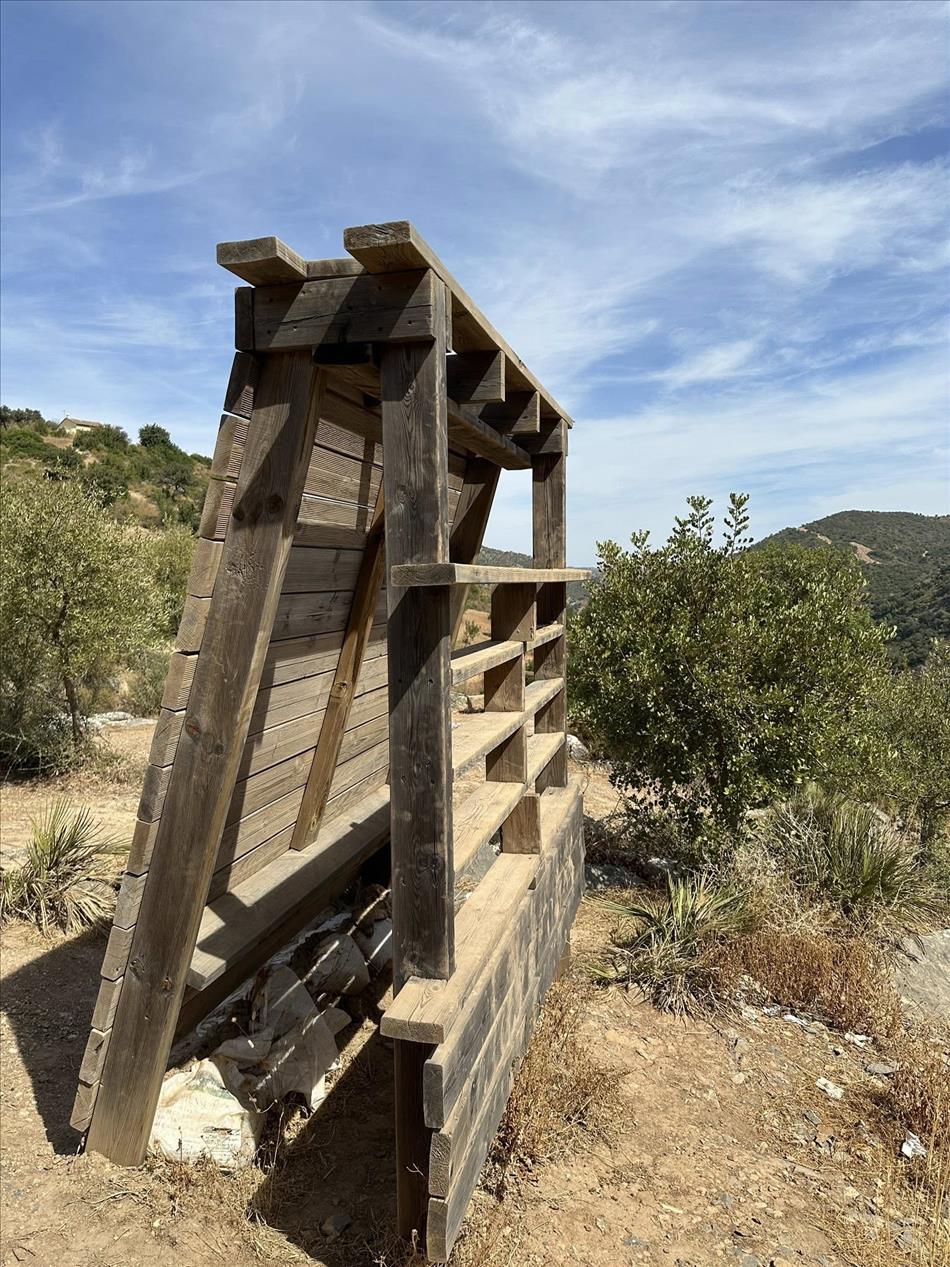 In the countryside, just on the hillside, a wooden structure that looks like a solitary unused wall