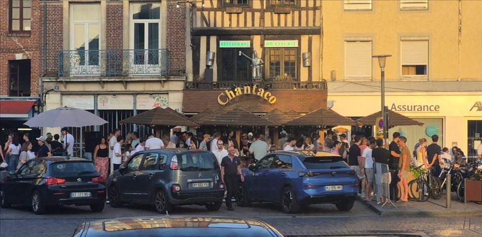 A restaurant with tables outside, filled with people and super busy