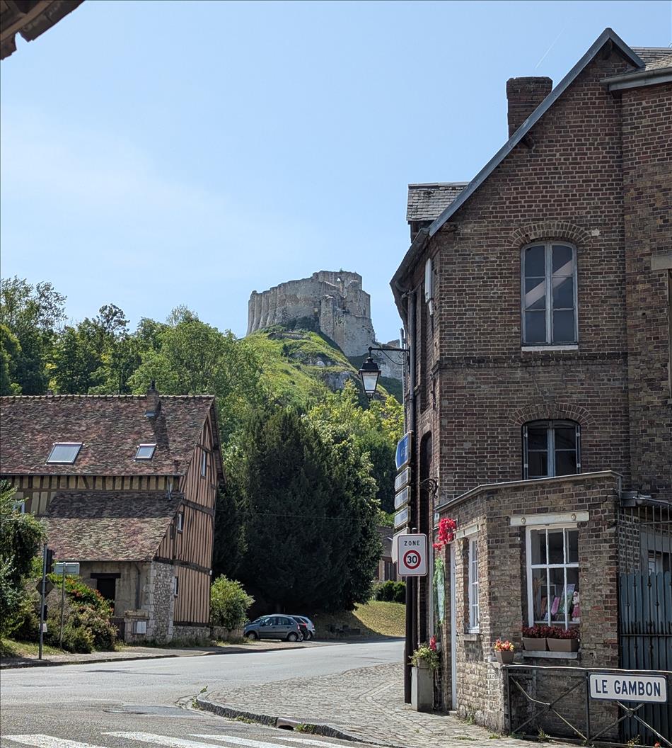 seen between houses a large blocky castle atop a steep hill
