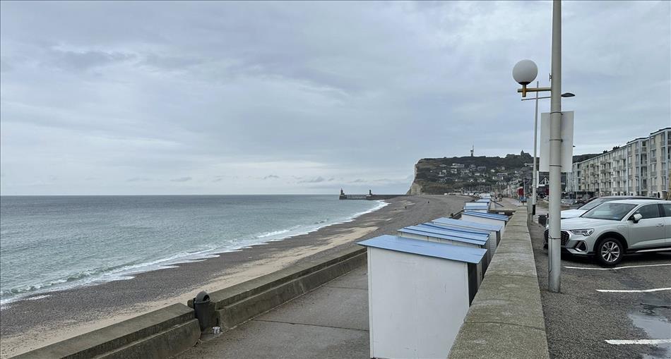 A harsh drab concrete sea wall, the beach, heavy skies and grey sea at Fecamp