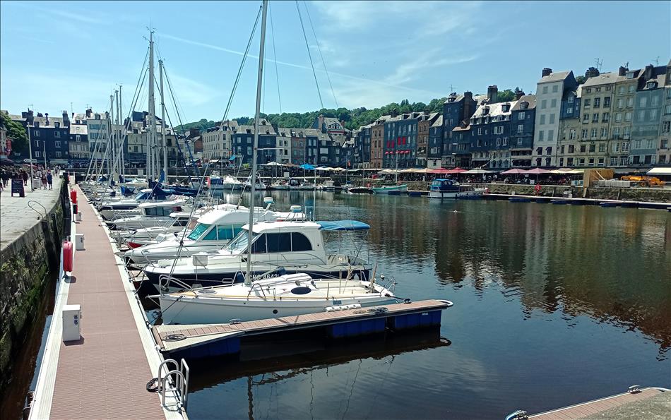 Sailing boats in the harbour, tall old buildings around the edge and sun canopies for the diners