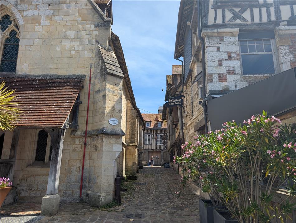 A narrow cobbled lane between the walls of an ancient church and historical houses