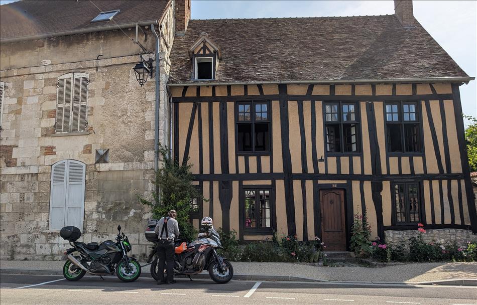 Ren locks the bikes beside 2 old french houses, one timber framed and one stone