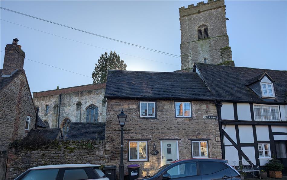Some old stone houses with the Church tower above behind them