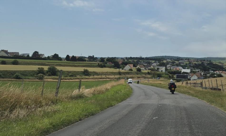 Sharon and Ren riding through French countryside with fields and a few houses