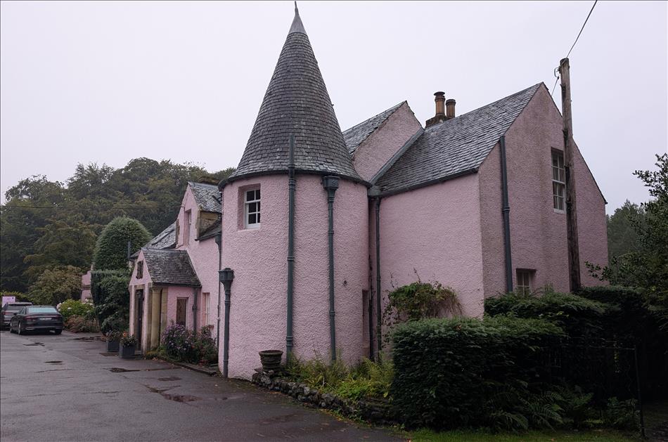 A house renedered and painted pink with a curious diney style round turret in the front