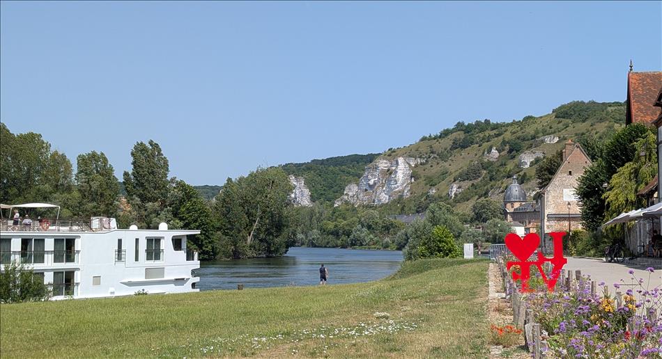 The edge of a large low River Cruise ship, the river, and the surroundings are pretty