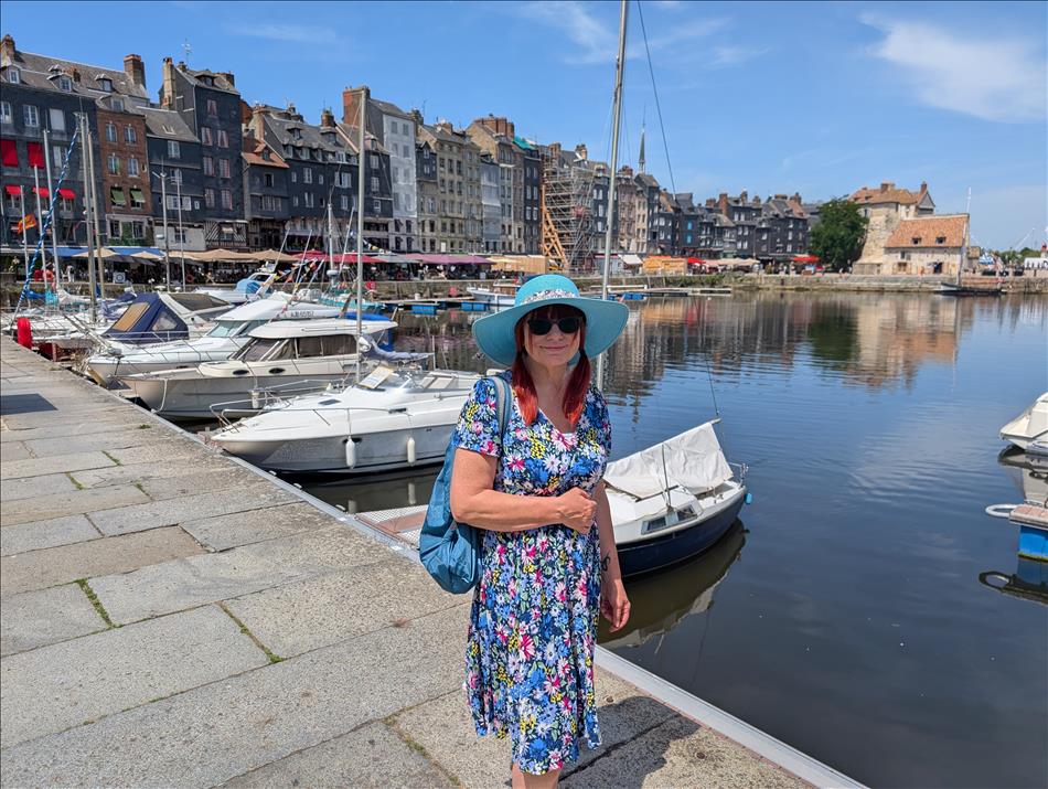 Sharon in a blue summer dress, sunglasses and broad rimmed hat at the Honfleur harbour