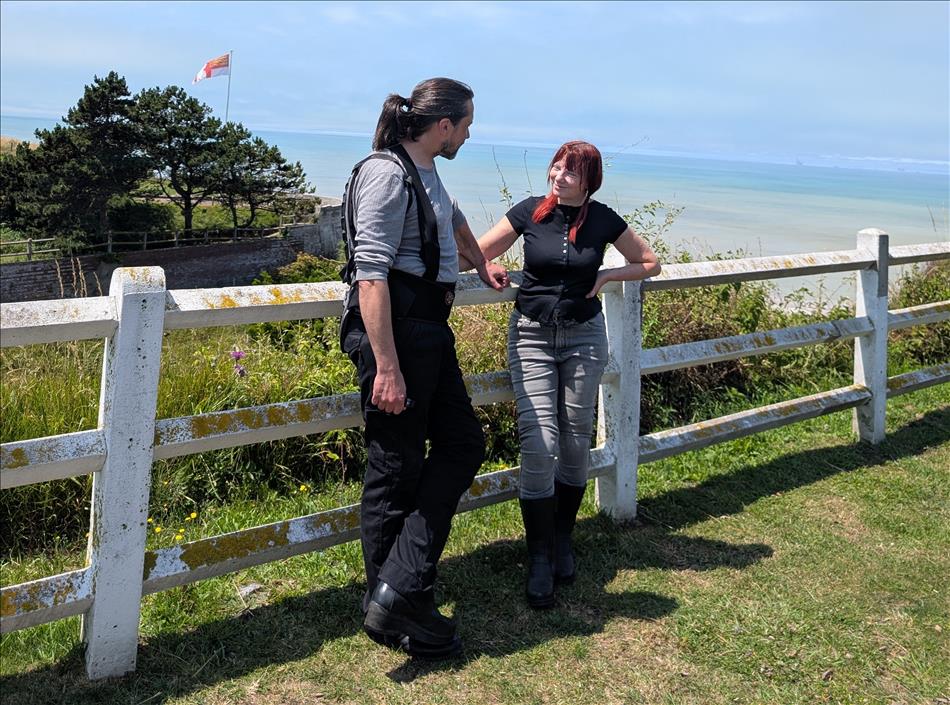 Sharon and Ren chat beside a fence overlooking the ocean in glorious sunshine