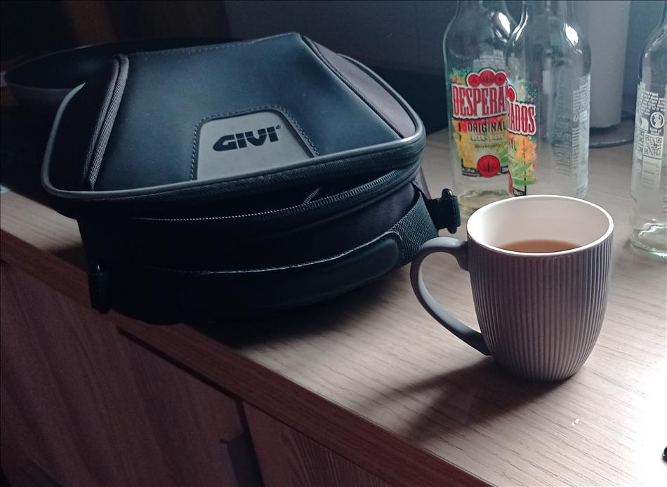 A small cup of tea beside Ren's tank bag and some empty bottles