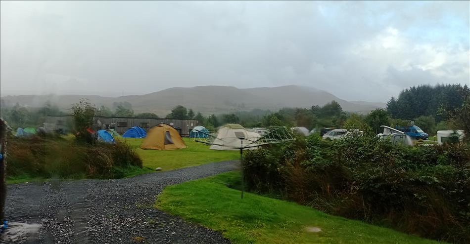 looking over a soggy campsite and hills covered in mist from a wet window